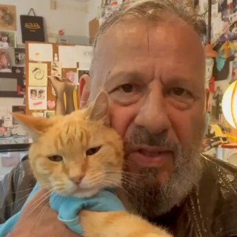 Charlie Schmidt holding Keyboard Cat in his art-filled studio
